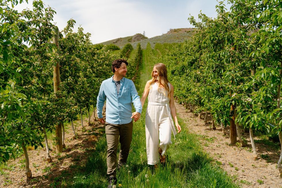 A couple holding hands walk through Davison Orchards in Vernon, B.C.