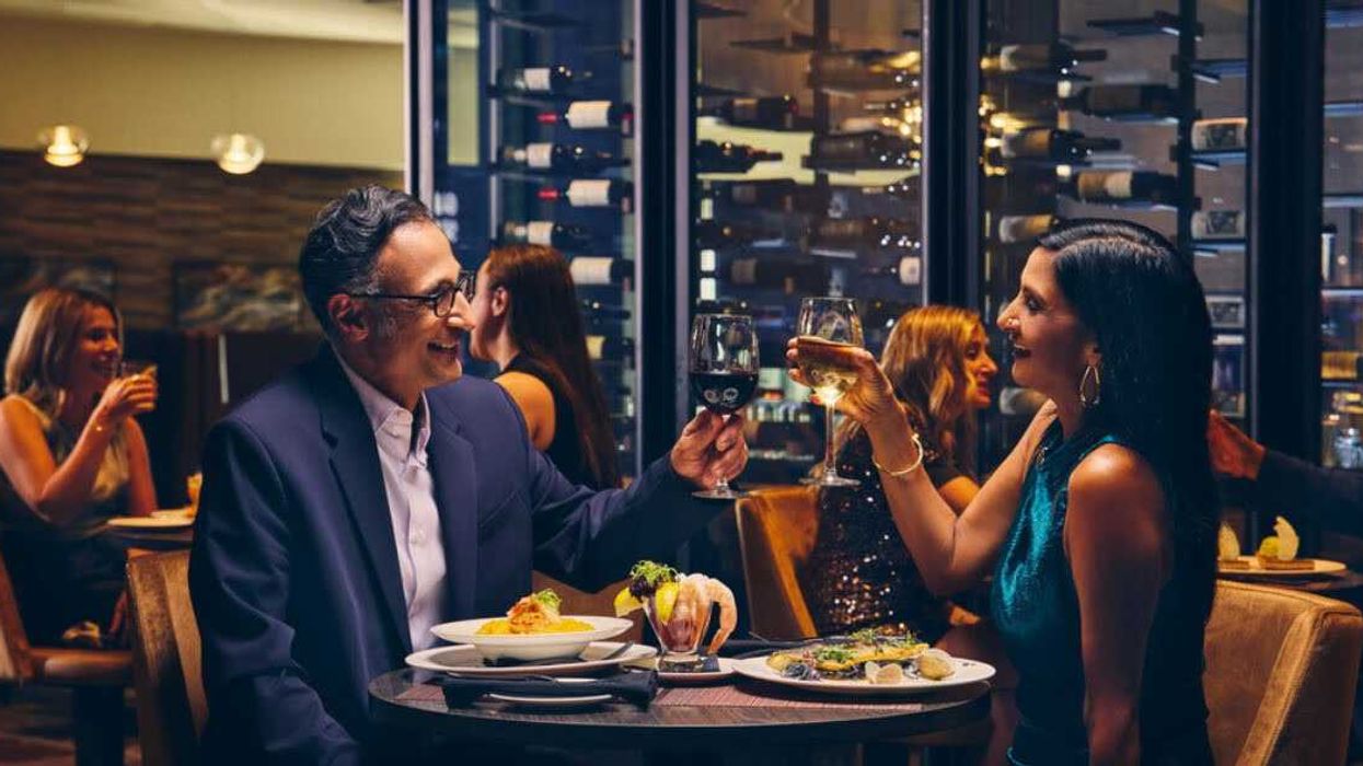 A couple in a restaurant raise their wineglasses to each other.