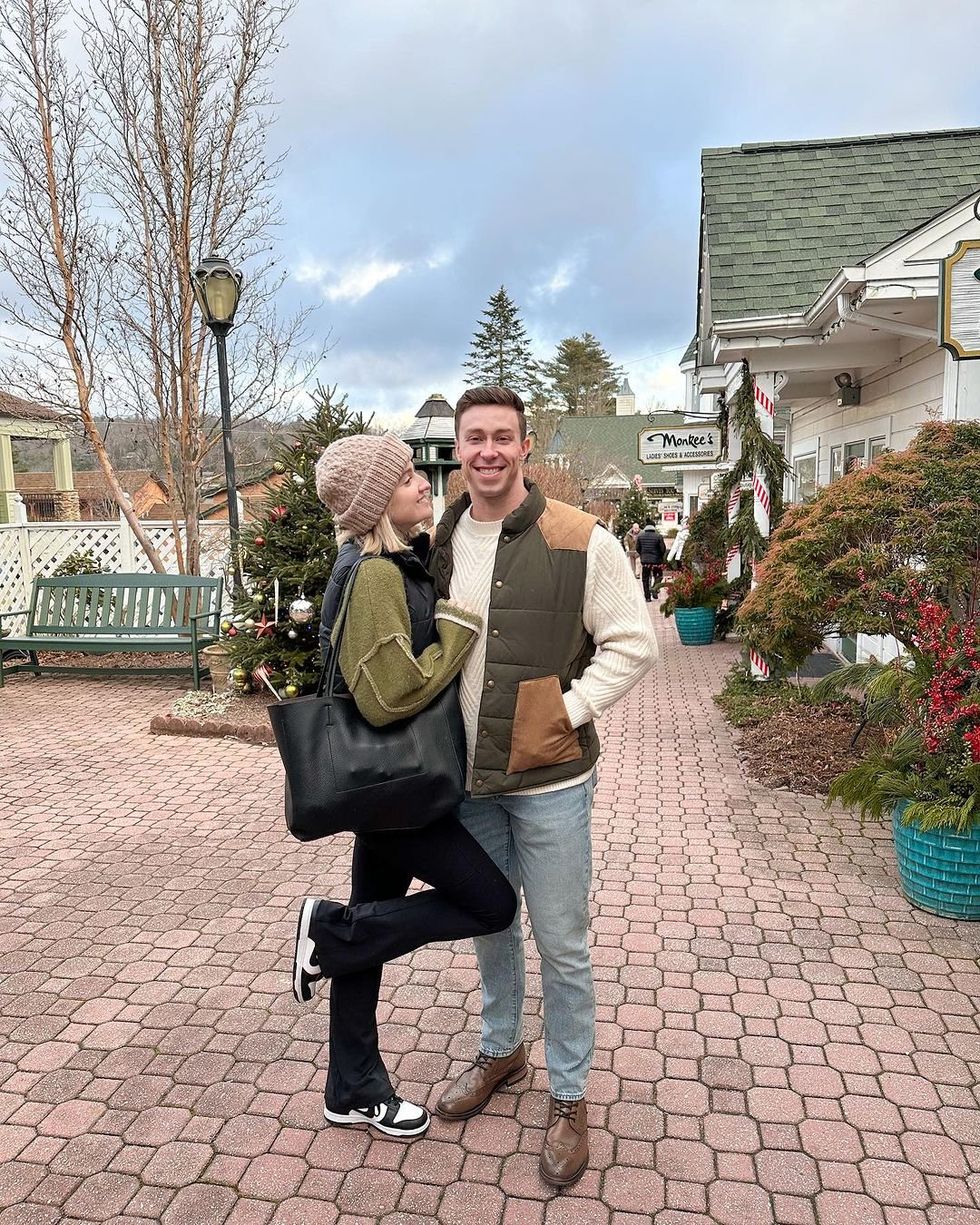 A couple pose and smile at the camera on the charming street of Blowing Rock, North Carolina.