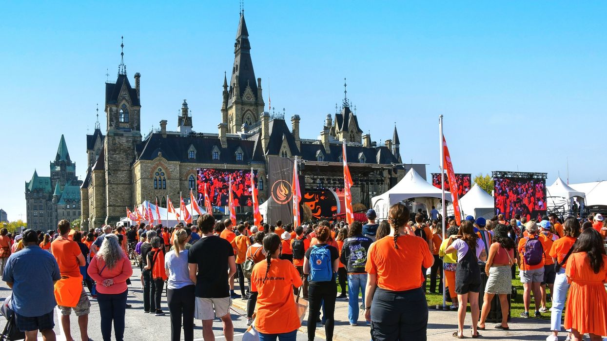 A crowd of people in orange shirts on Parliament Hill in Ottawa.