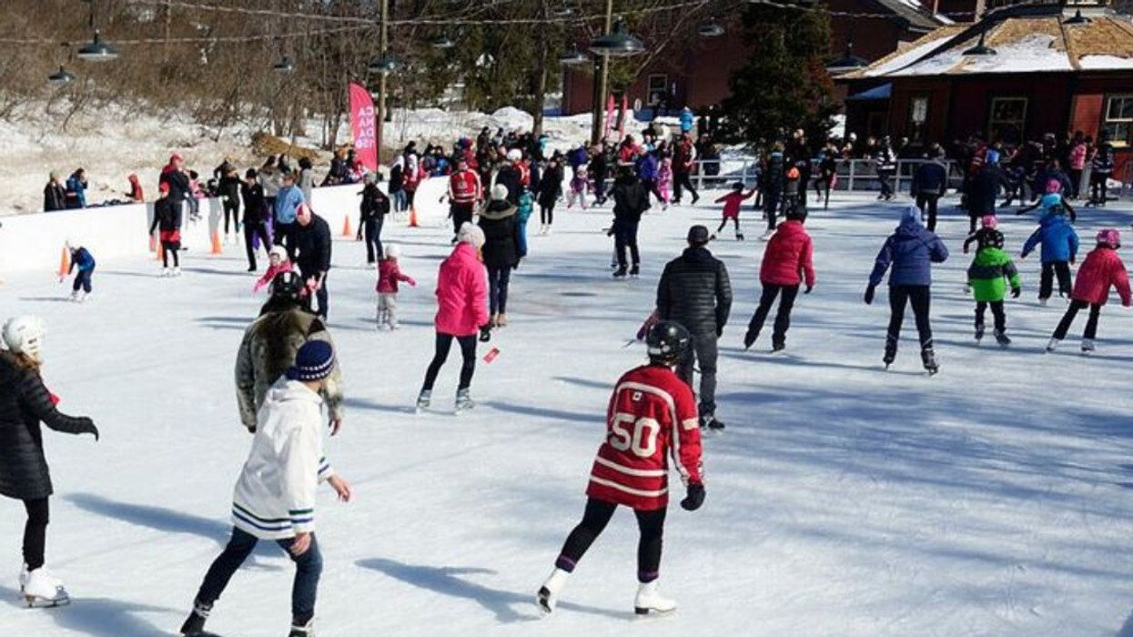 A crowd of people skating on an outdoor skating rink.