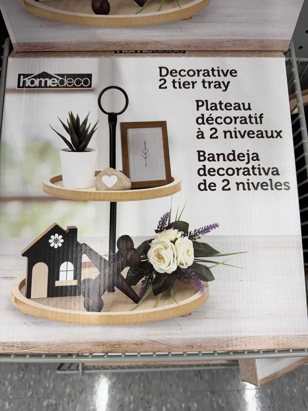 A decorative two-tier tray with pictures, flowers and other figurines stacked on top of it.