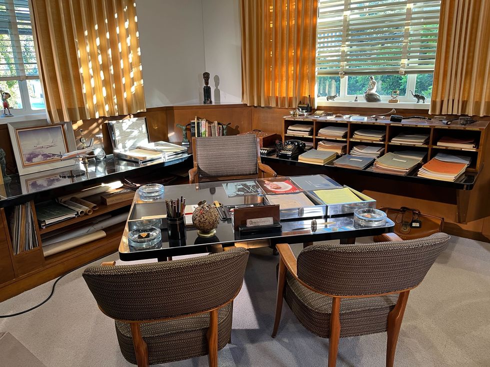 A desk with three chairs surrounded by documents and miniatures in the office of Walt Disney.