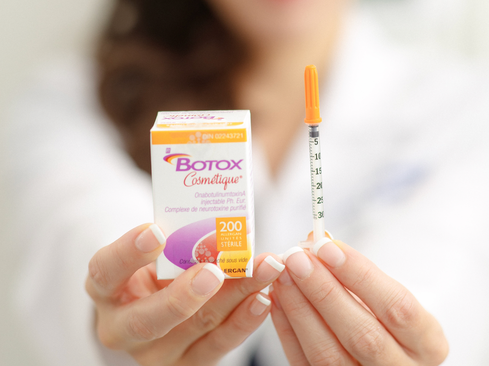 A doctor holding a box of botox and a syringe.