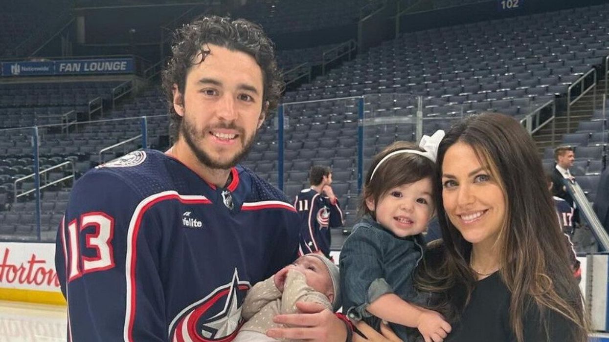 A family of four on an ice rink inside an empty arena.