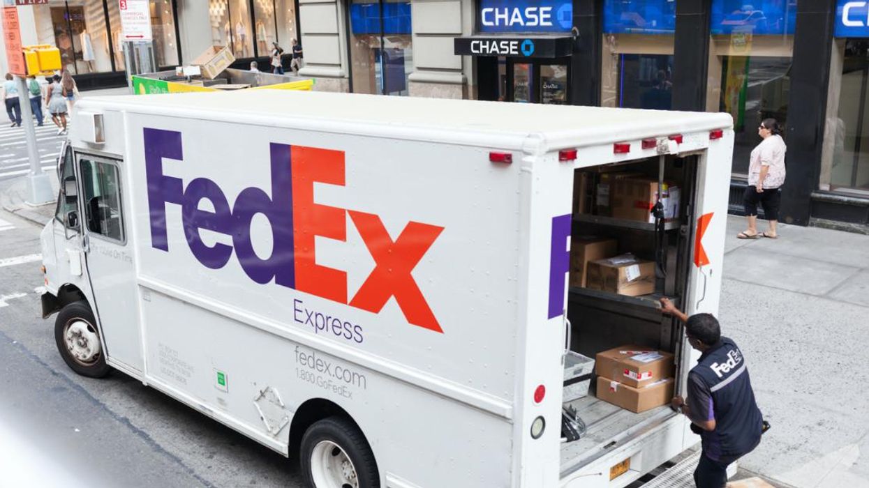 A FedEx worker loading a truck with packages. 