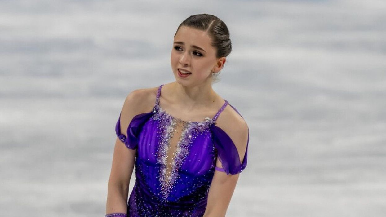 A female figure skater in a purple dress on the ice.