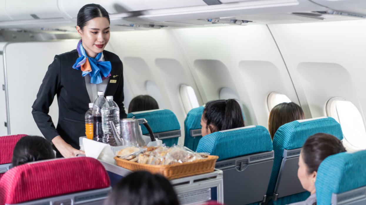 A flight attendant serving food on a plane.