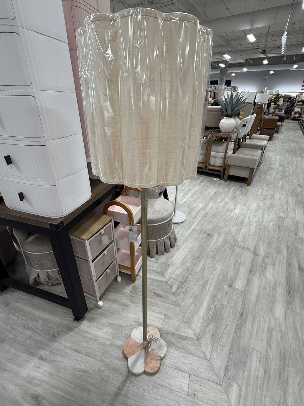 A floor lamp with a marble-type bottom and a beige lamp shade.