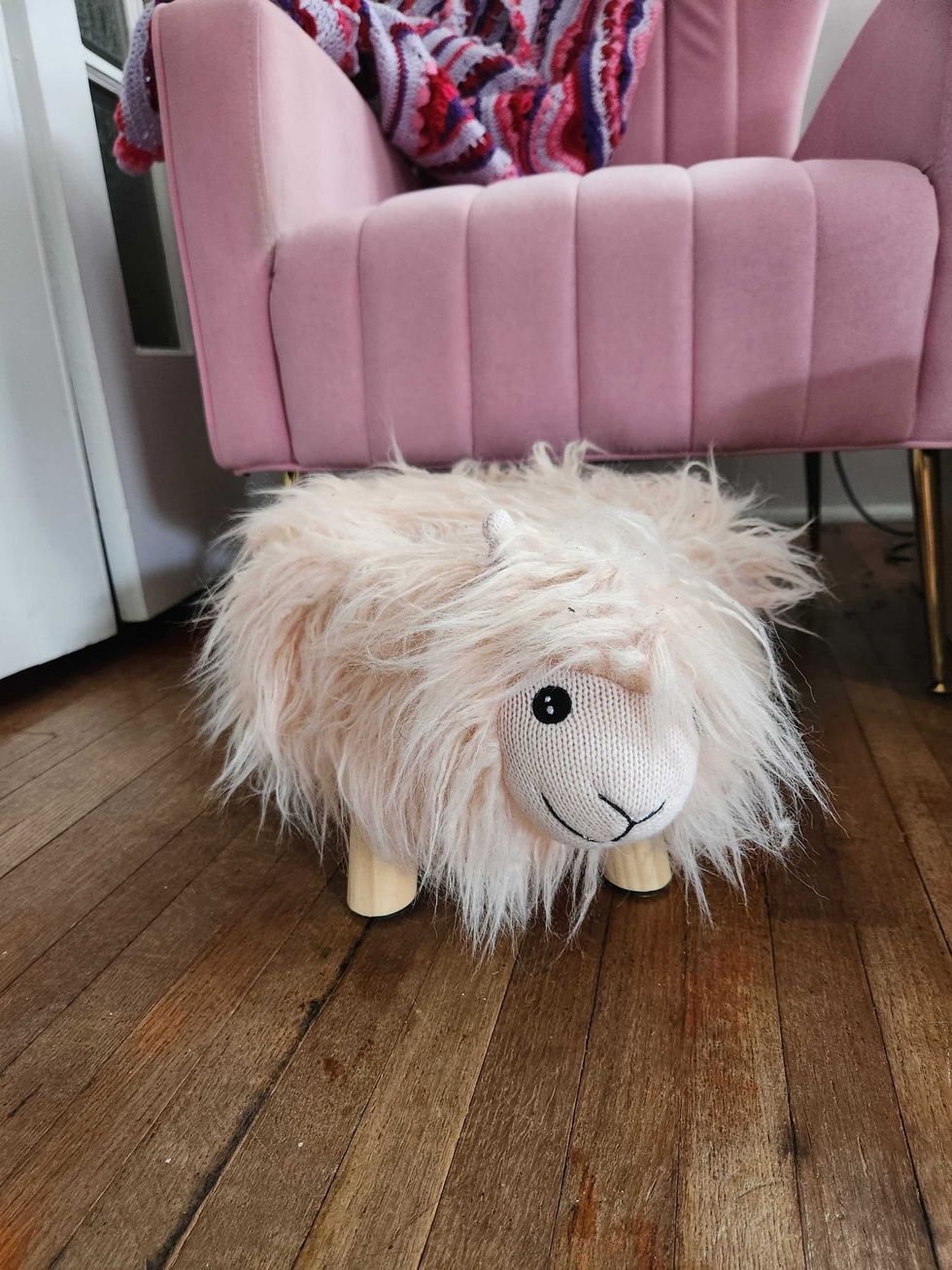 A fluffy pink sheep foot rest.