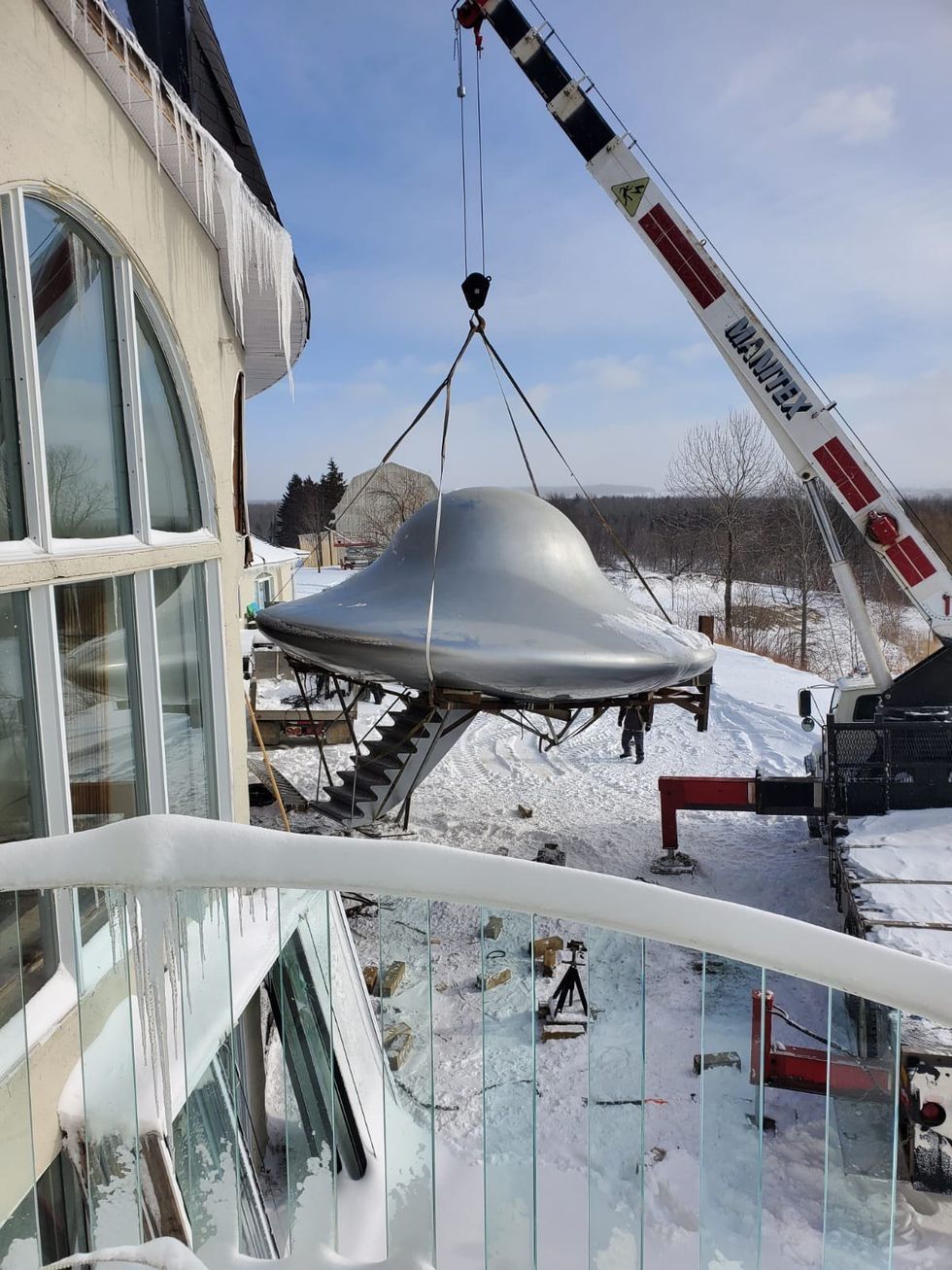 A flying saucer being hoisted by a crane in winter.