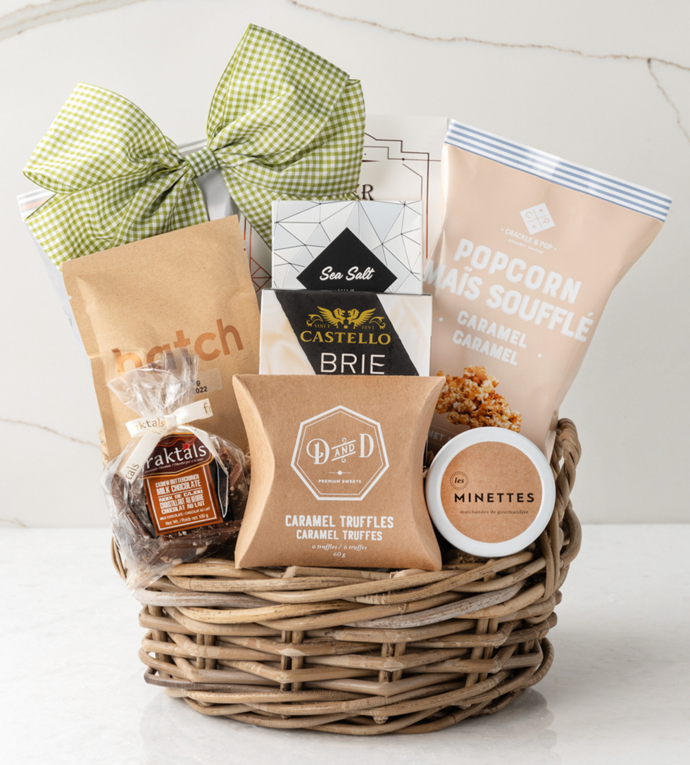 A gift basket with caramel truffles, brie cheese, popcorn and chocolate.