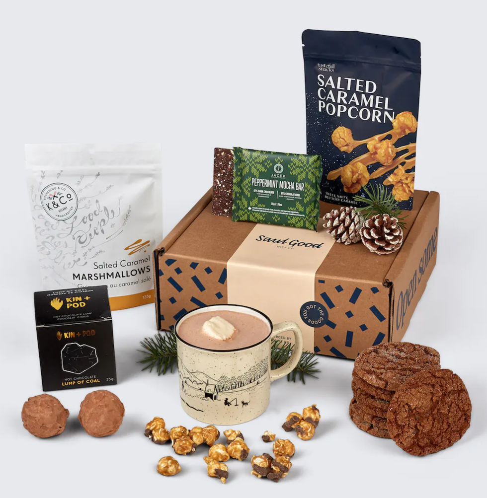 A gift box filled with hot chocolate, cookies, salted caramel popcorn and a marshmallow.