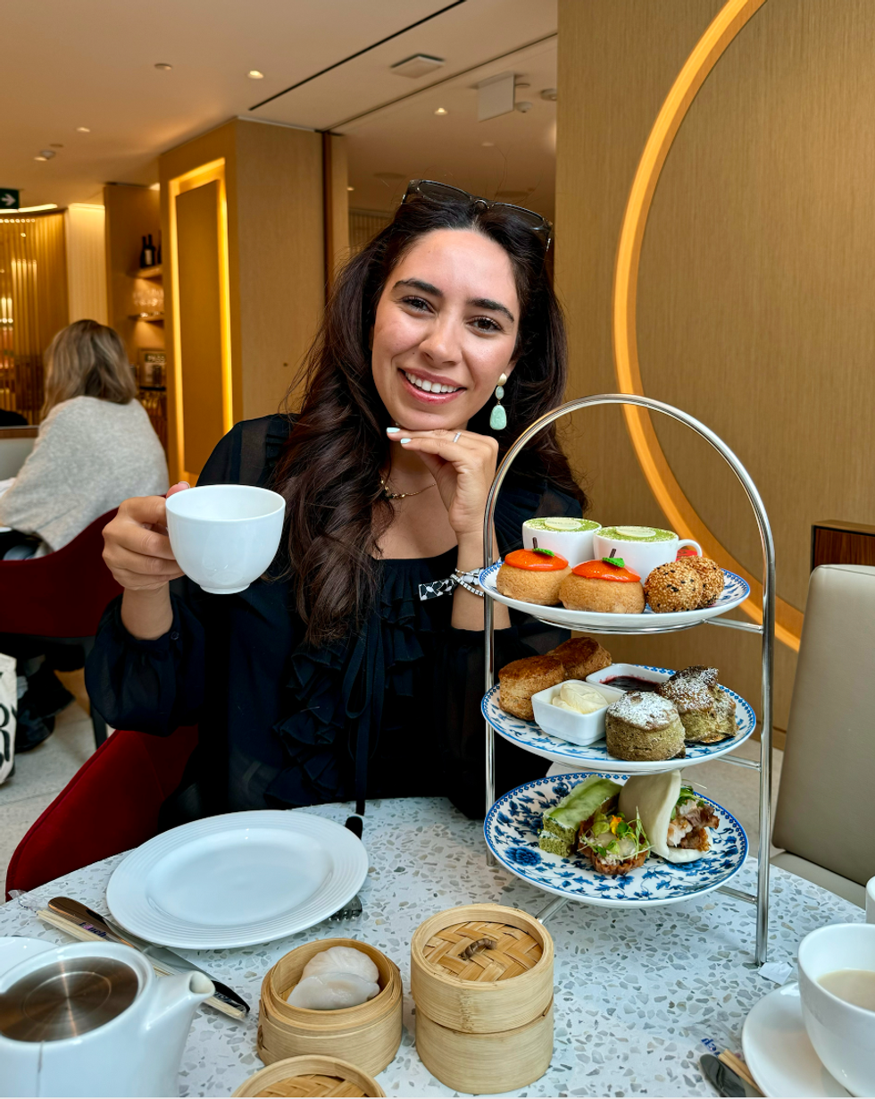 A girl holding tea and eating asian-inspired cuisine at an afternoon tea in Toronto.