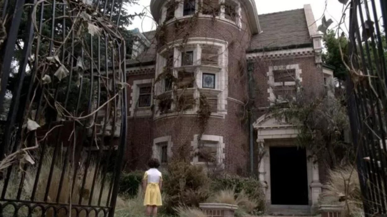 A girl in a yellow skirt standing outside American Horror Story's "Murder House."
