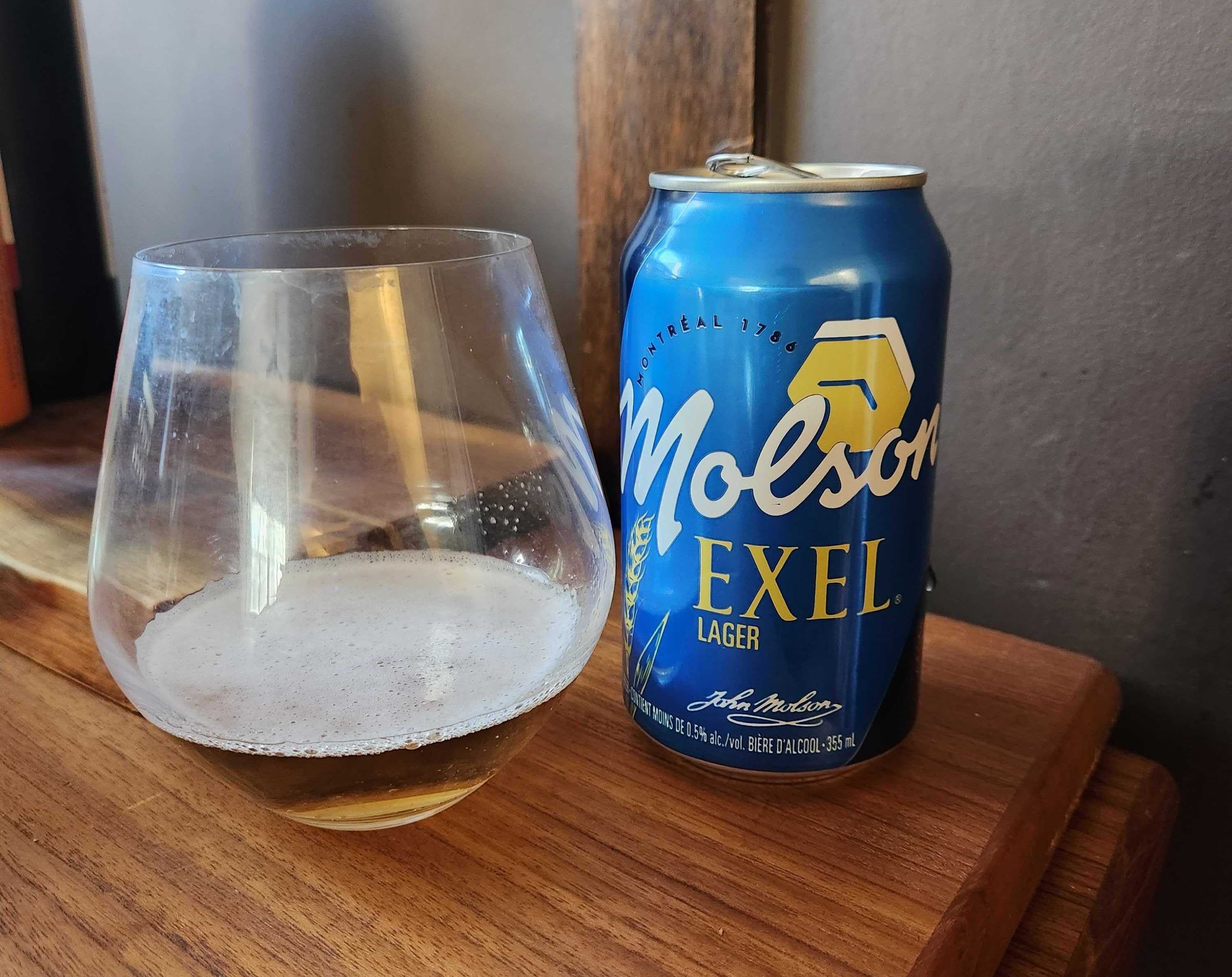 A glass of Molson Exel Lager beside a can of Molson Exel Lager on a wooden table.