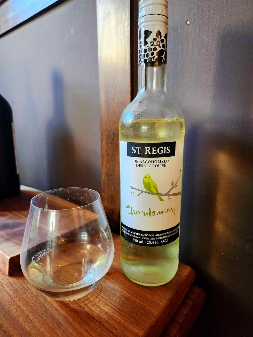 A glass St. Regis Chardonnay and a bottle of St. Regis Chardonnay on a wooden table.