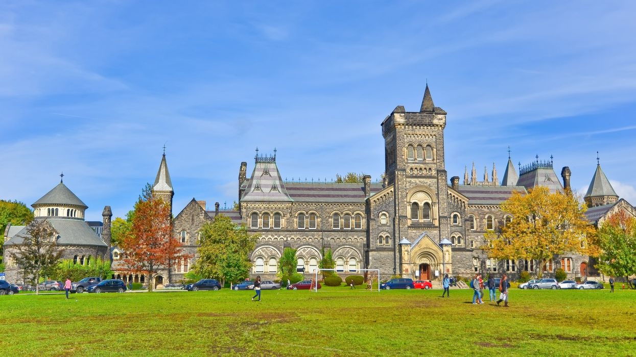 A gothic-style university campus building with a soccer field out front.