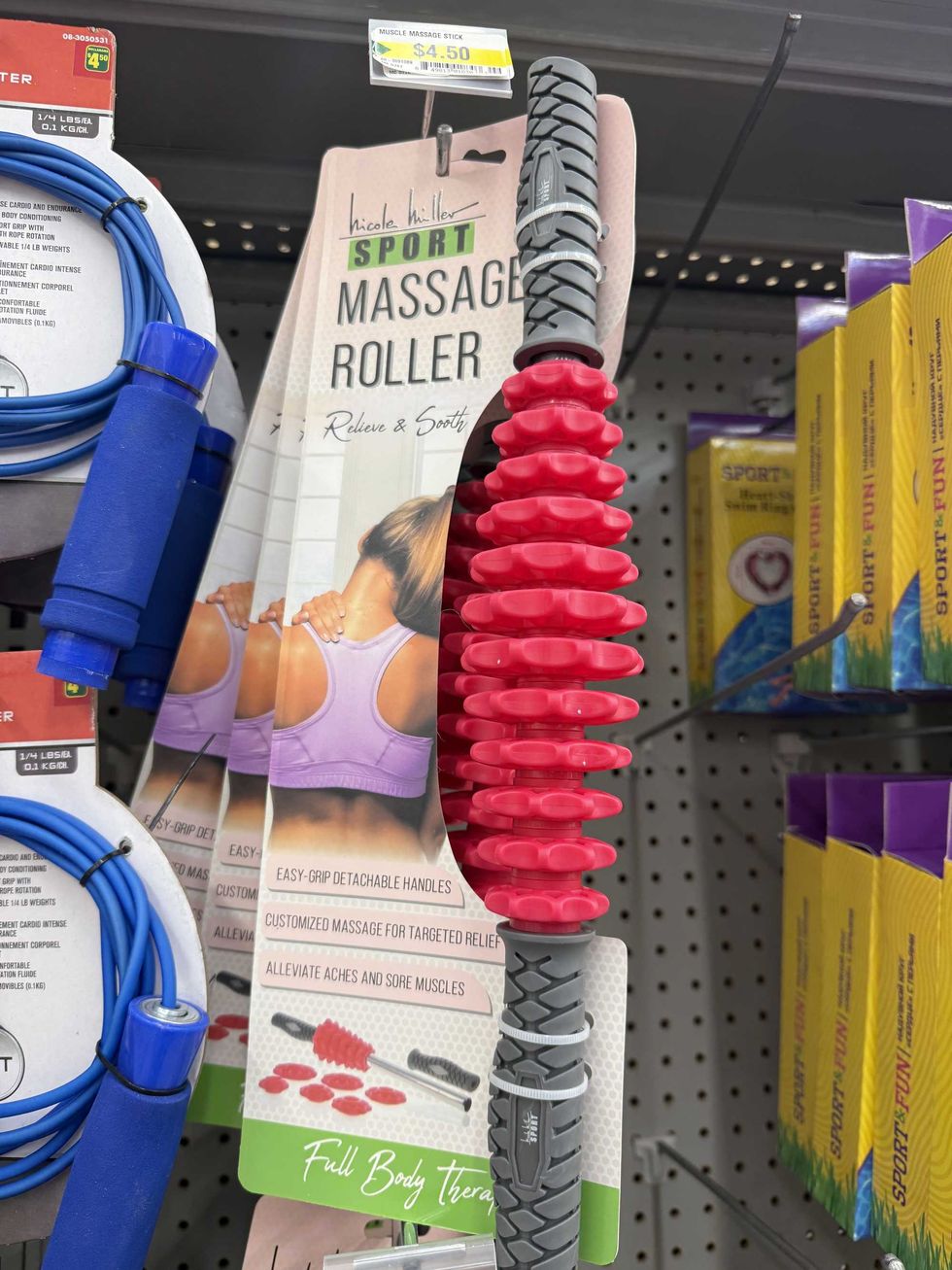 A grey and pink rod attached to a tag that has a woman touching her shoulder that says sport massage roller on it.