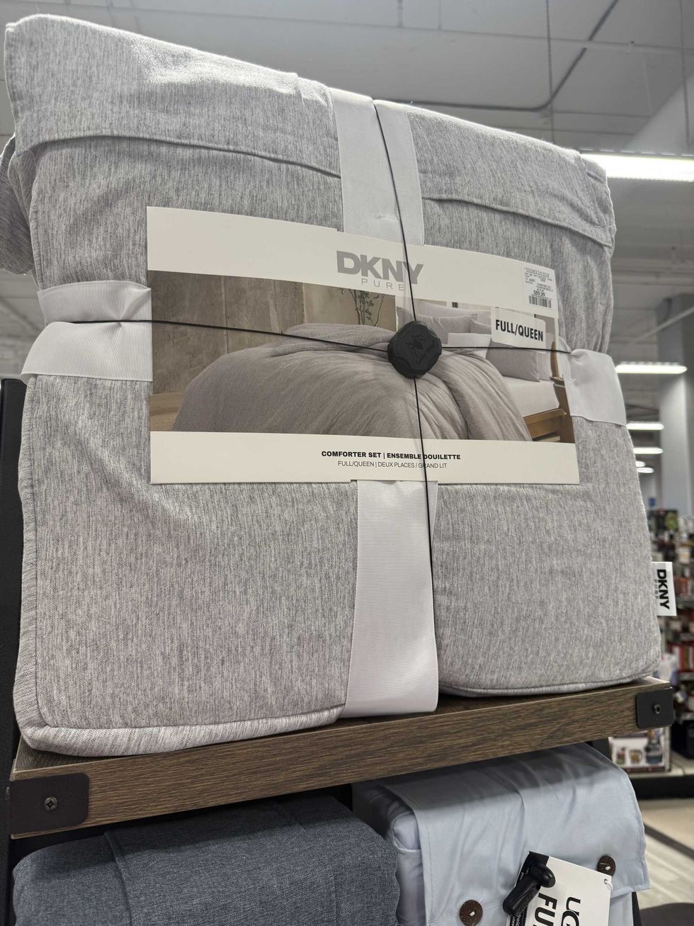 A grey comforter set with a label that reads full/queen and DKNY Pure.