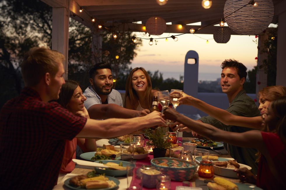 A group of people having dinner on a patio and having a toast.