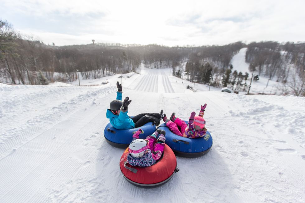 A group of people sitting in snow tubes.\u200b