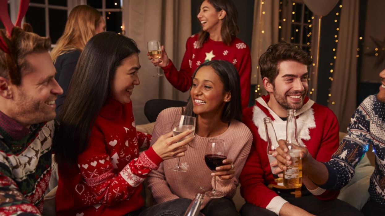 A group of people wearing Christmas sweaters and holding drinks at a holiday party.