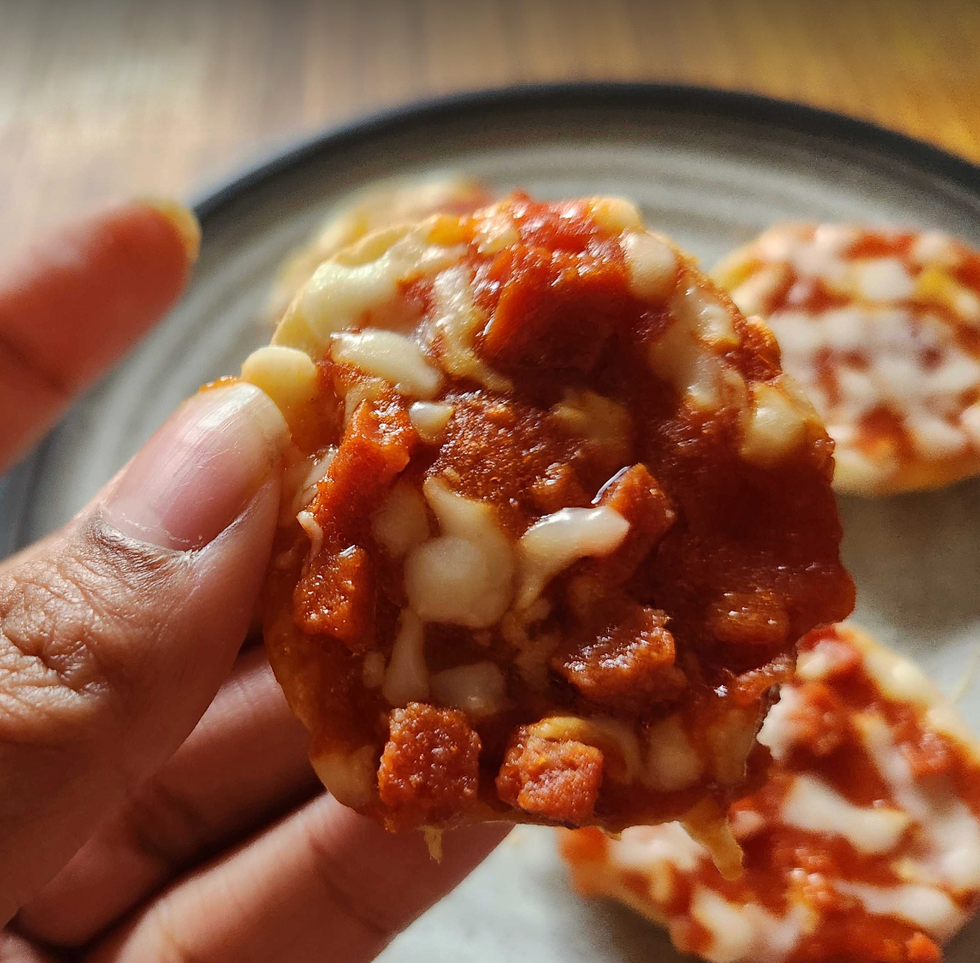 A hand holding a Bagel Bite.