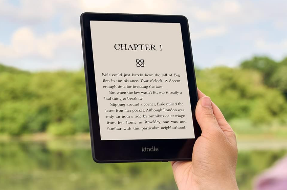 A hand holding a black Kindle.