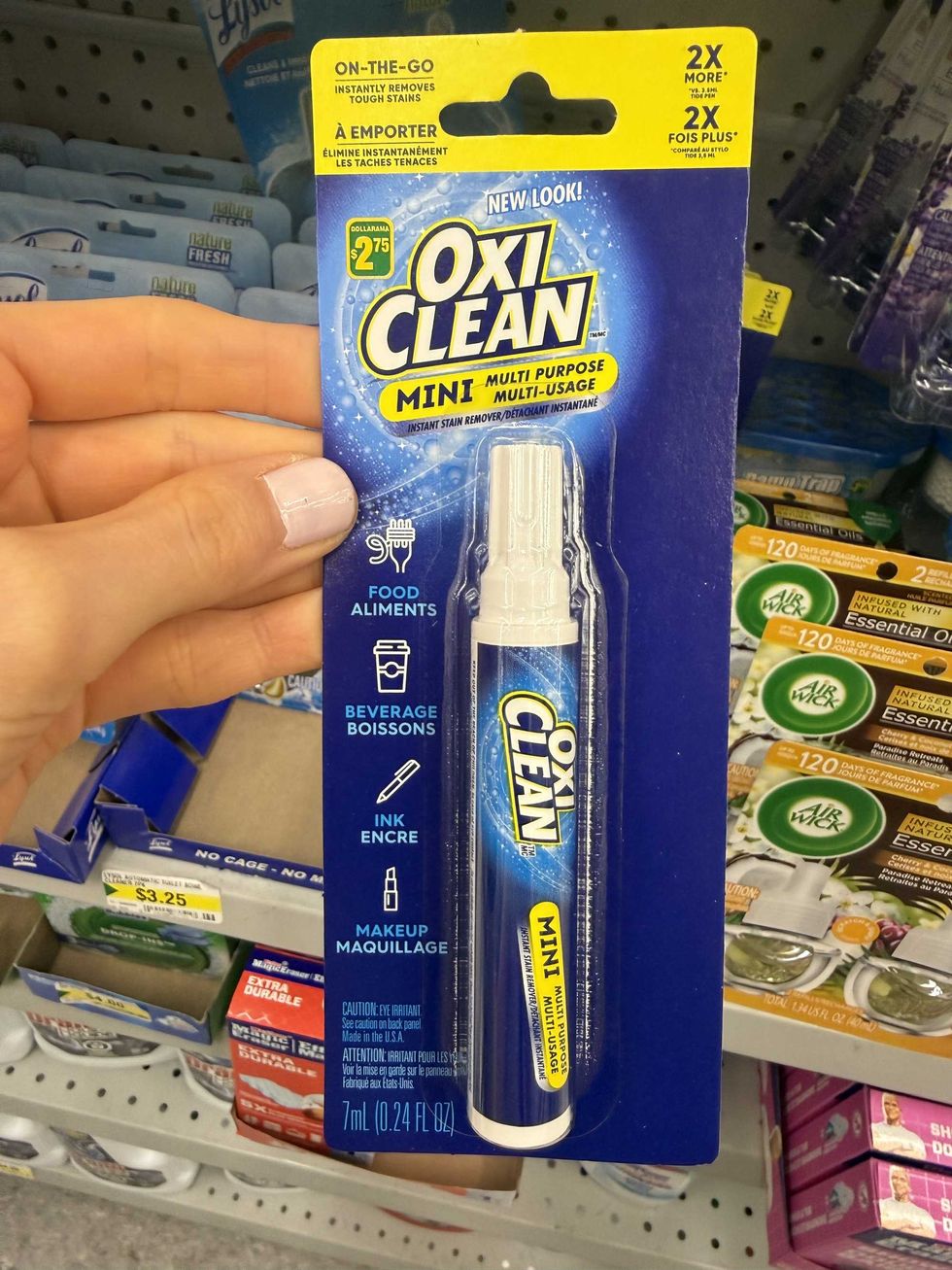 A hand holding a blue and white pen that says mini multi-purpose instant stain remover pen.