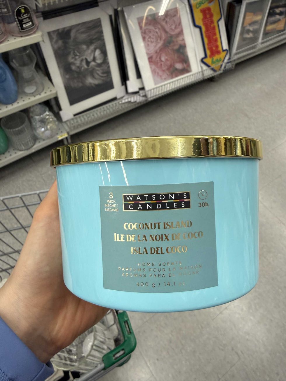A hand holding a blue jar with a gold lid.