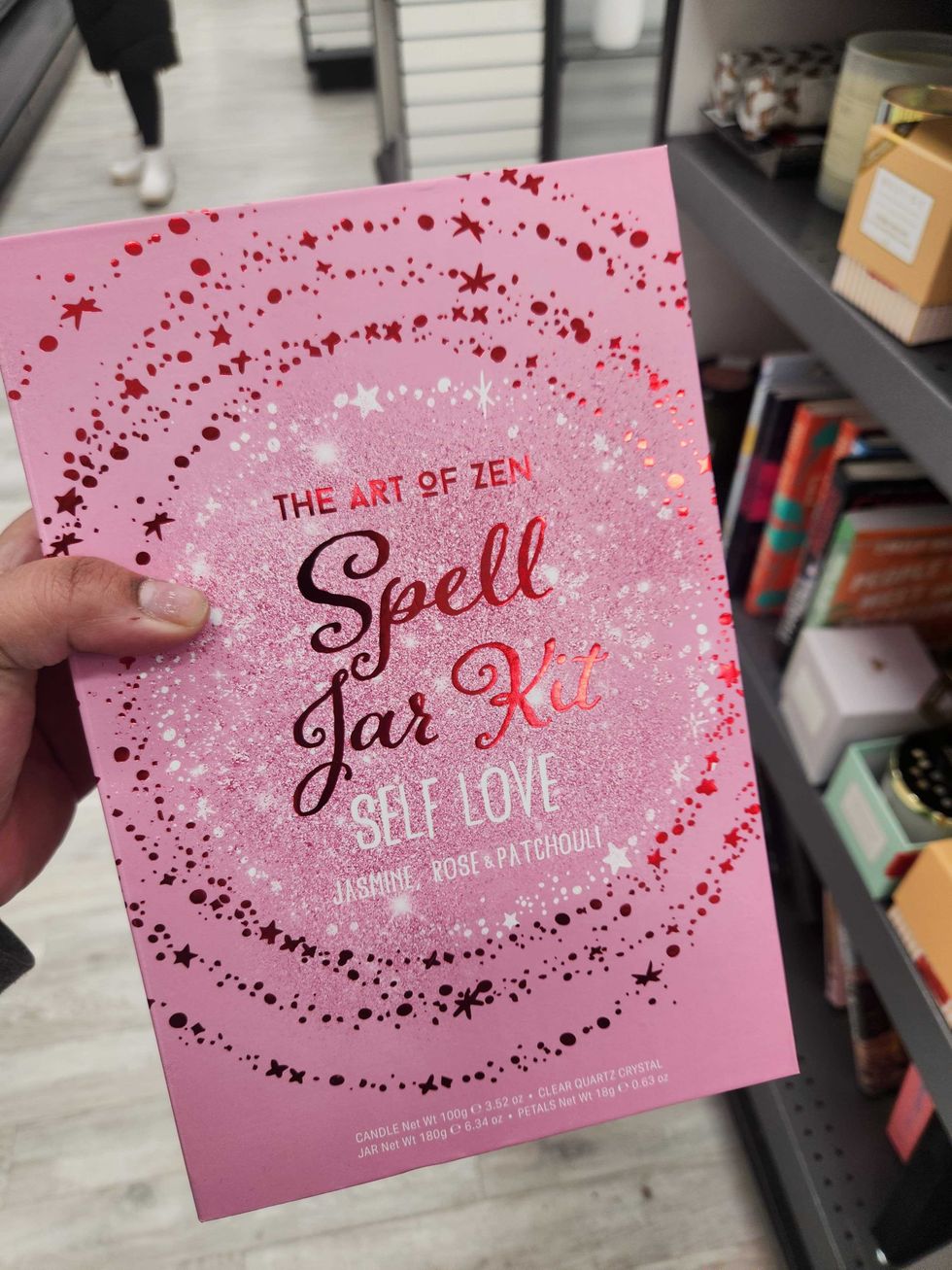 A hand holding a book that says The Art of Zen: Spell Jar Kit Self Love.
