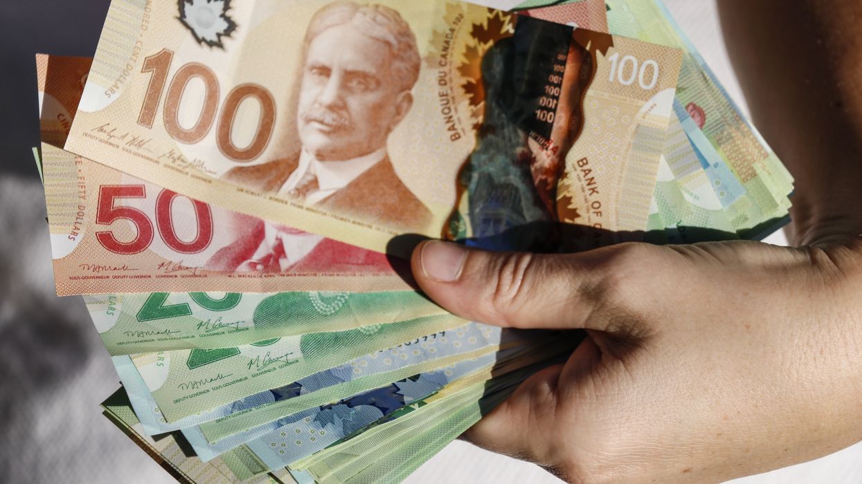 A hand holding a collection of Canadian bills (illustrative).