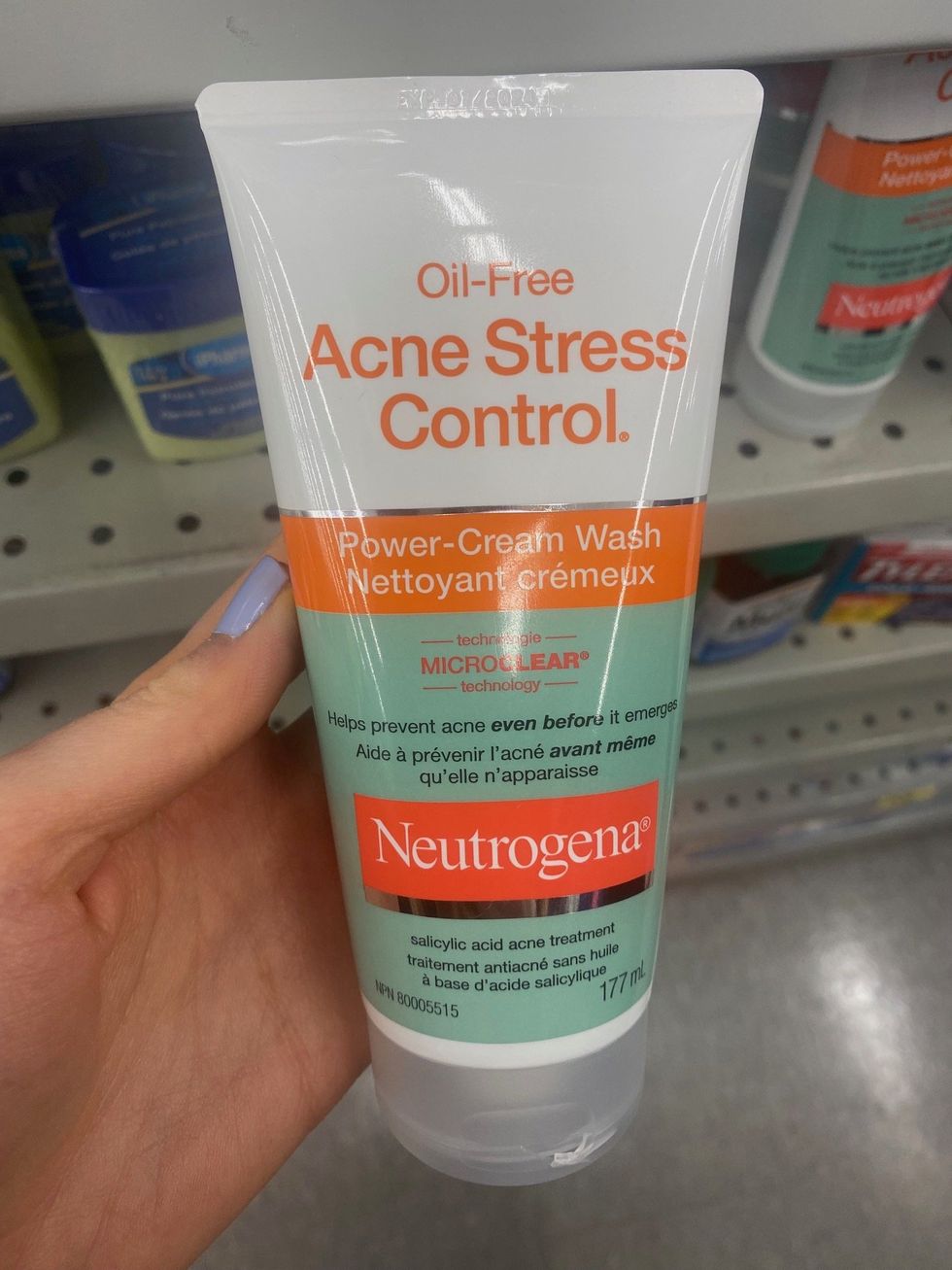 A hand holding a face wash on sale at a store.