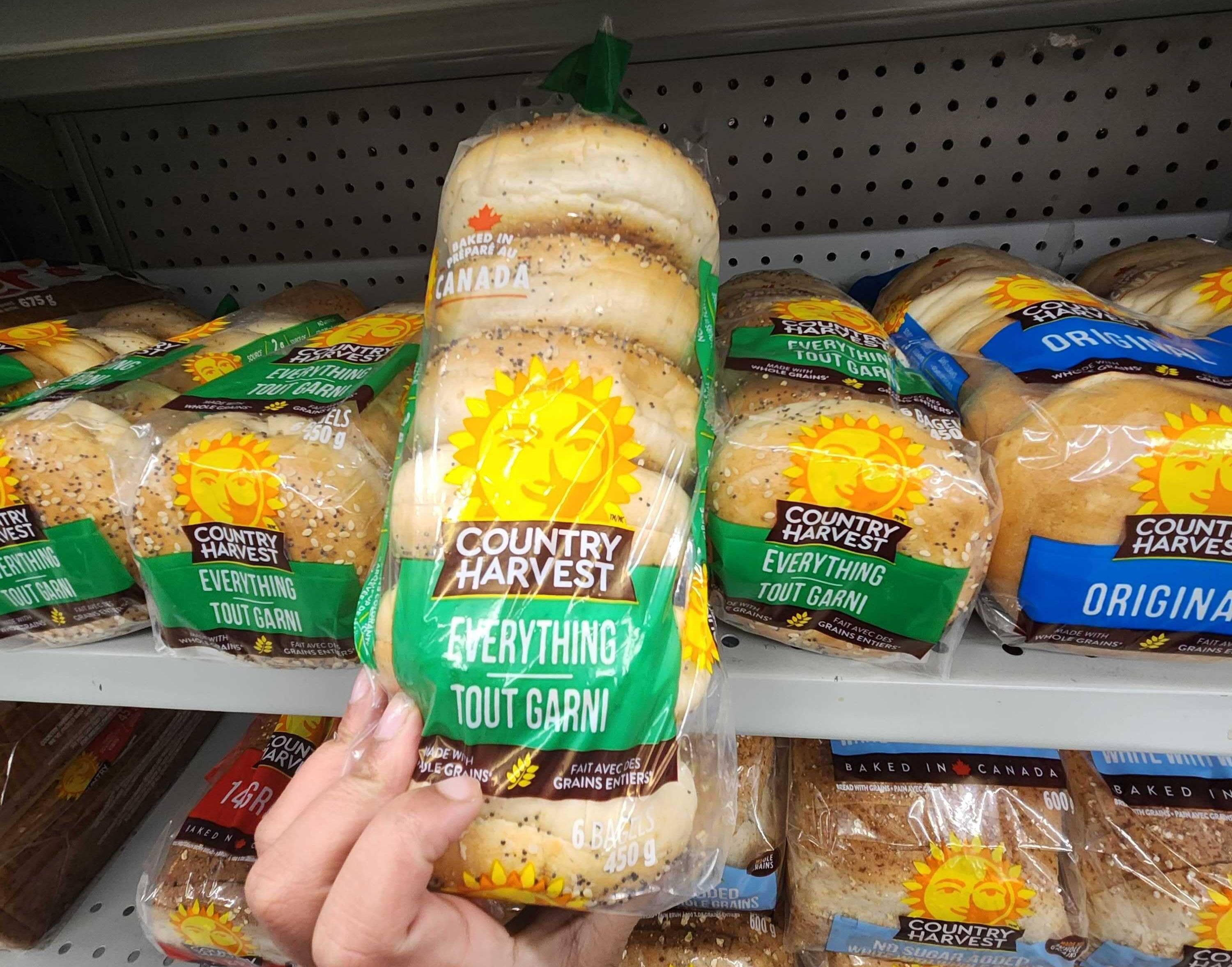 A hand holding a oackage of \u200bCountry Harvest Everything Bagels.