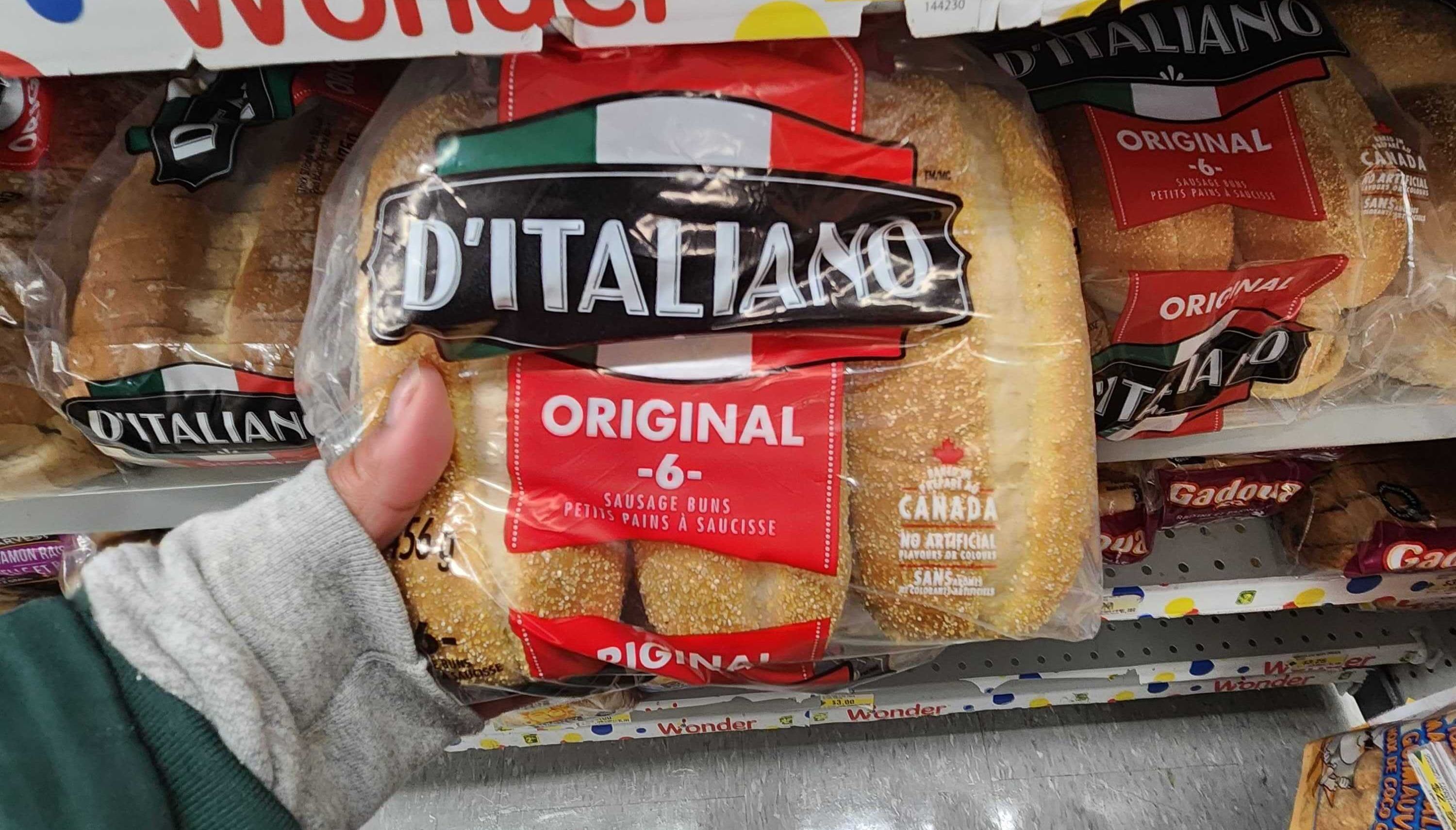 A hand holding a package of D'Italiano Sausage Buns.