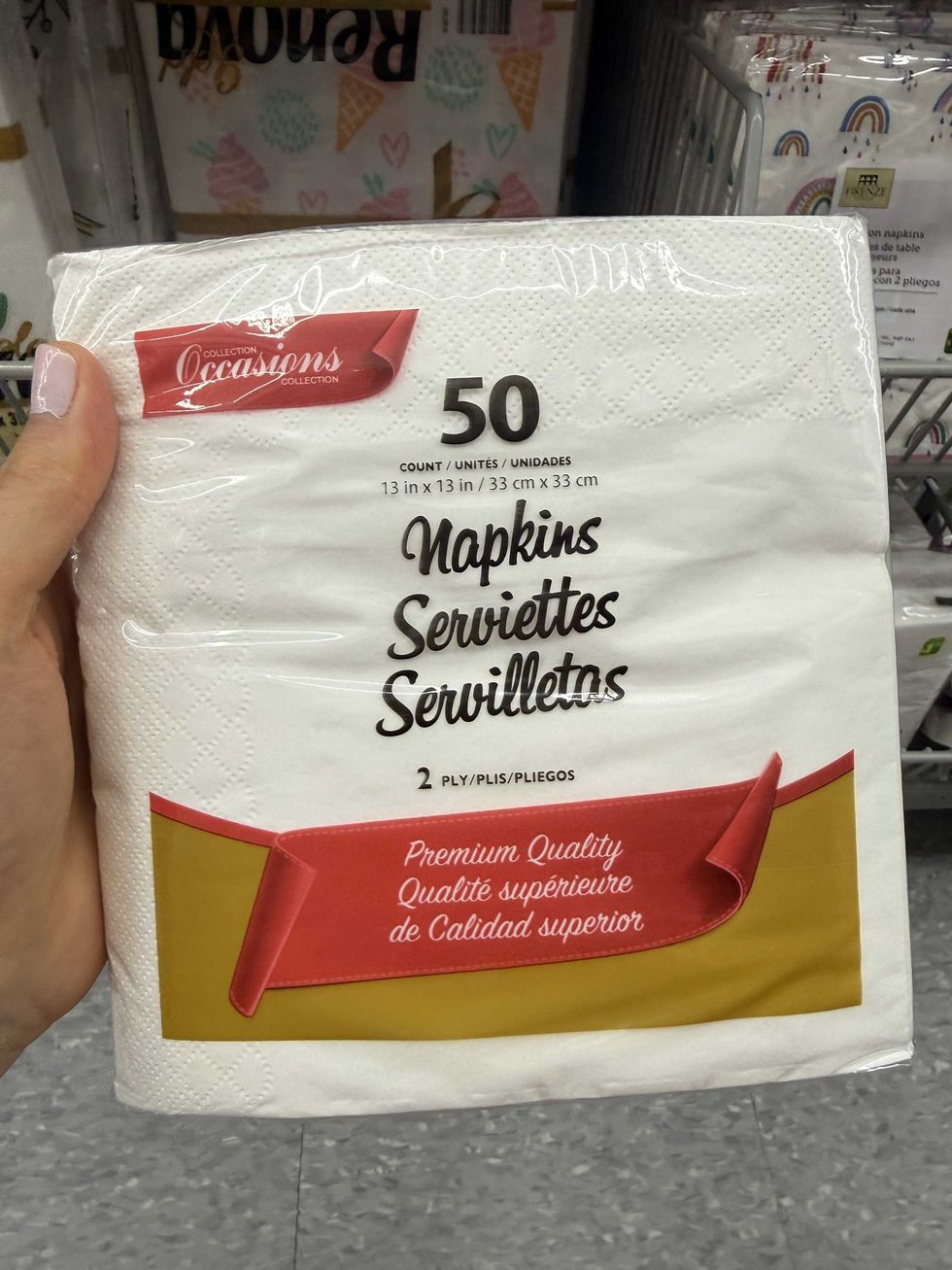 A hand holding a package of white napkins.