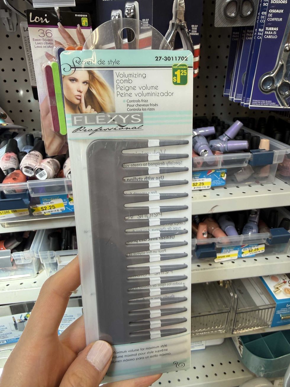 A hand holding a package with a comb inside it.