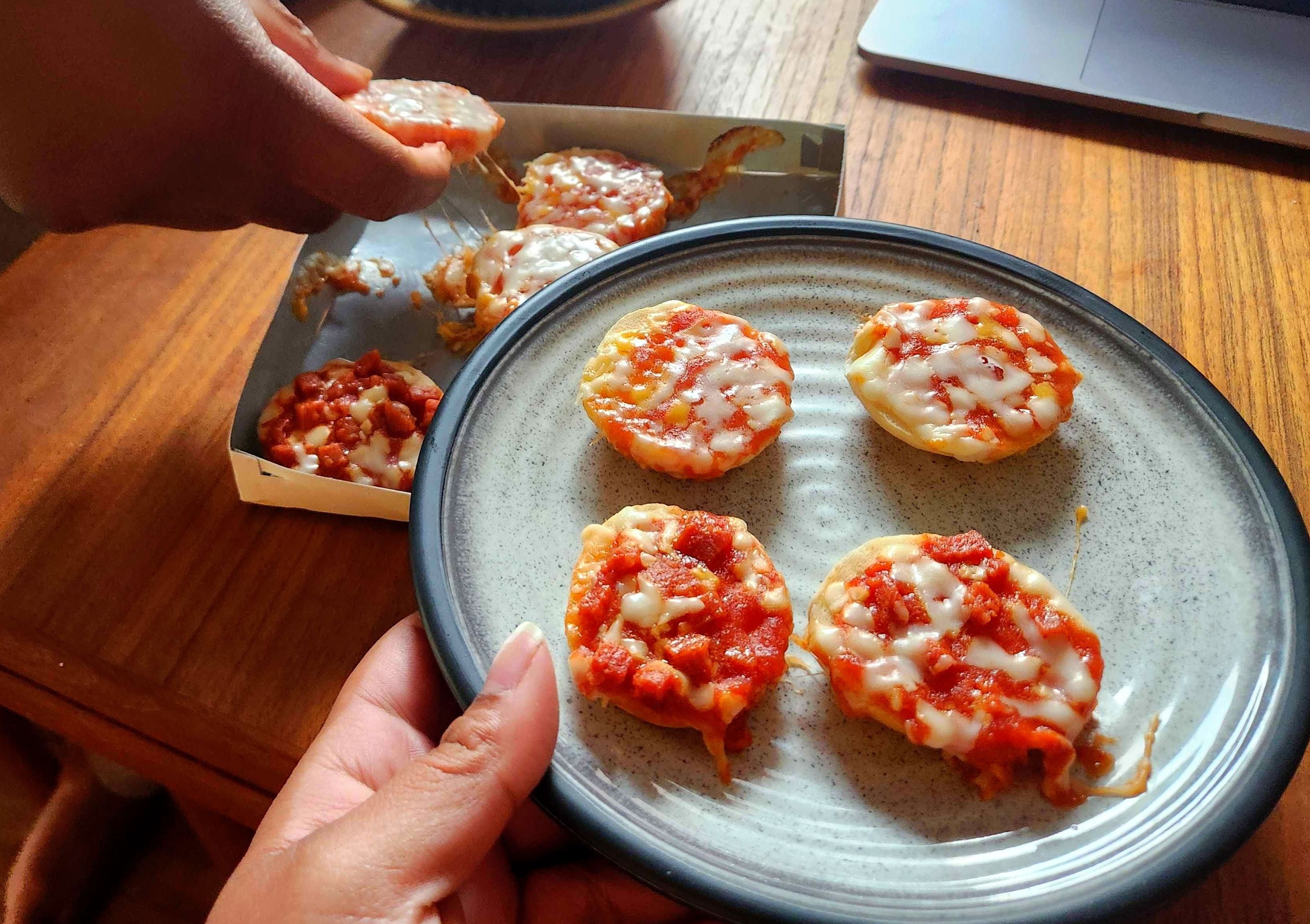 A hand holding a plate of Bagel Bites.