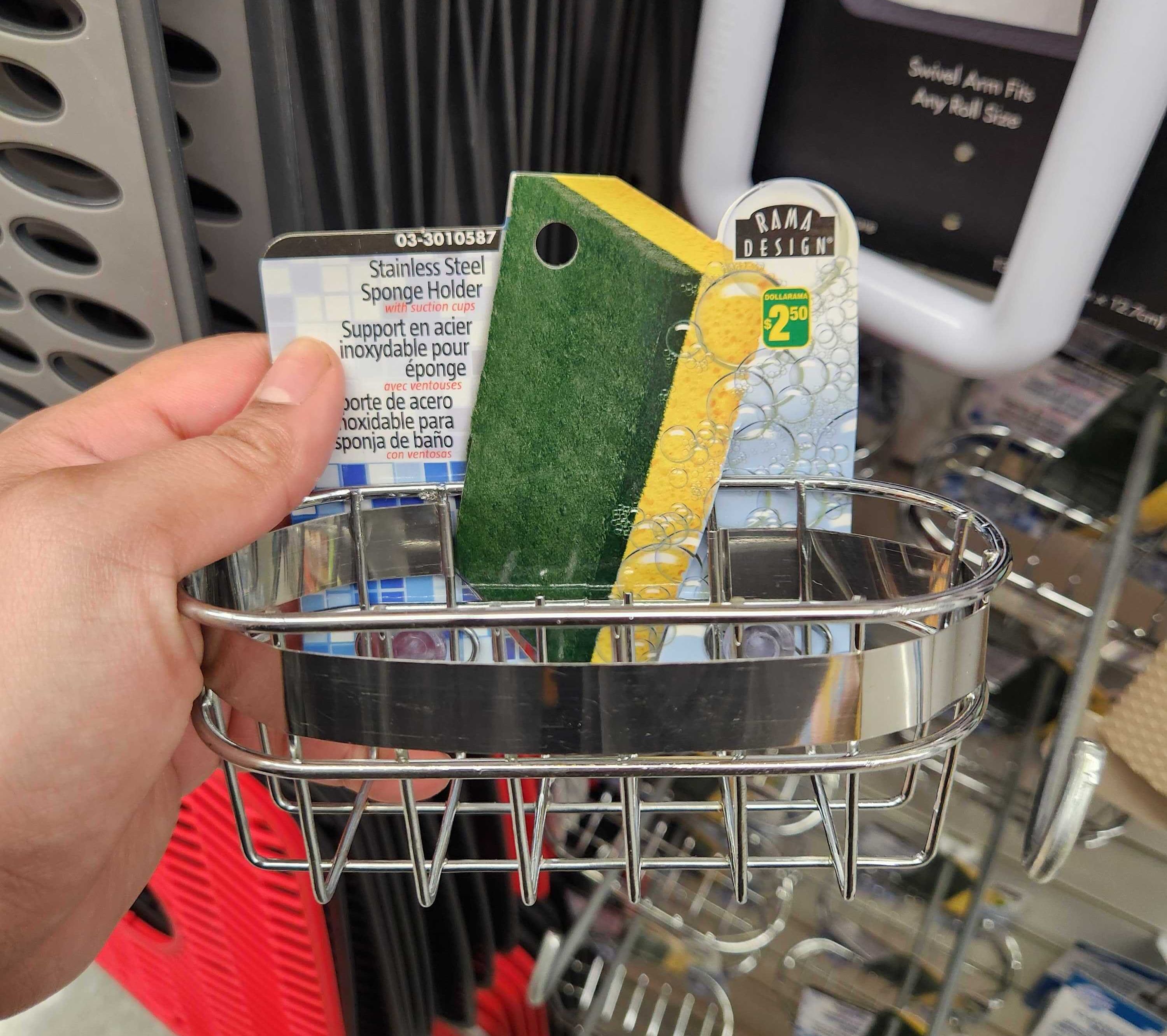 A hand holding a stainless steel sponge holder.