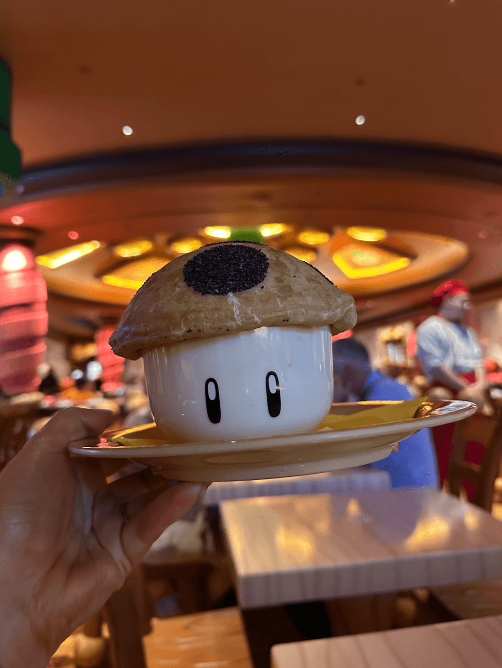 A hand holding a Toad-shaped ceramic bowl filled with the Super Mushroom Pizza Bowl.