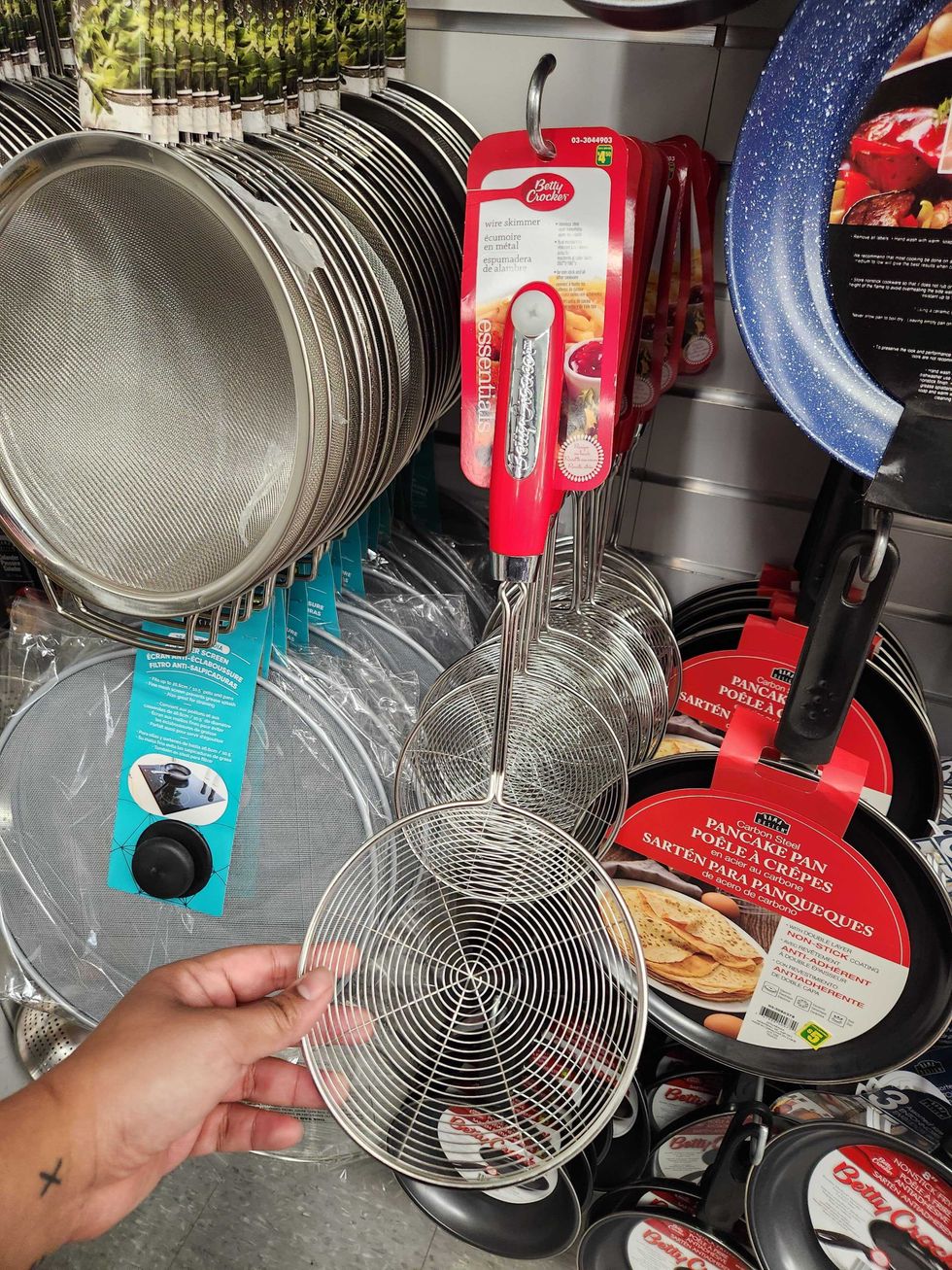 A hand holding a \u200bwire skimmer.