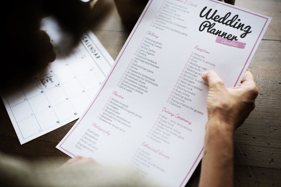 A hand holding a wedding planner checklist.