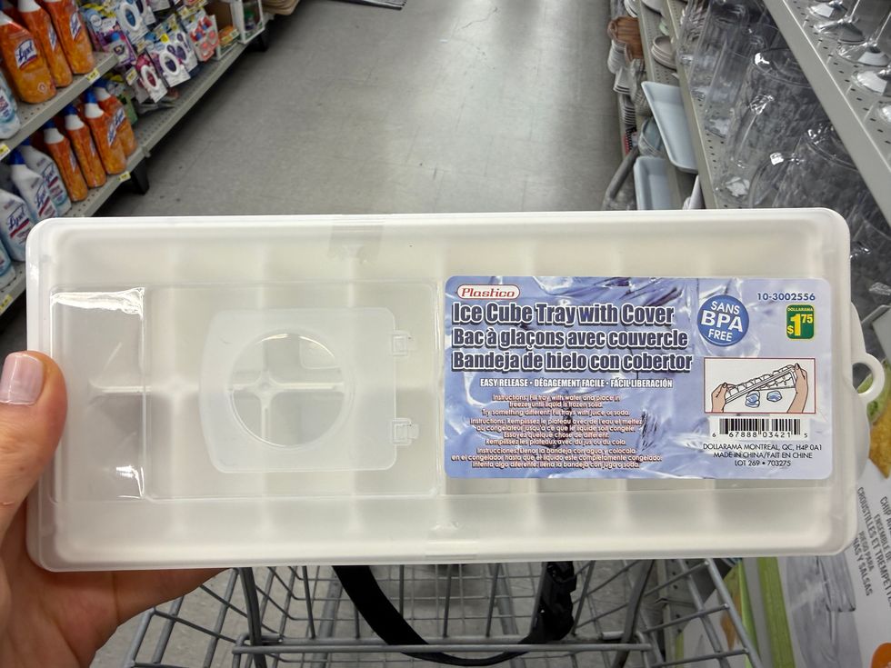 A hand holding a white ice cube tray with cover.