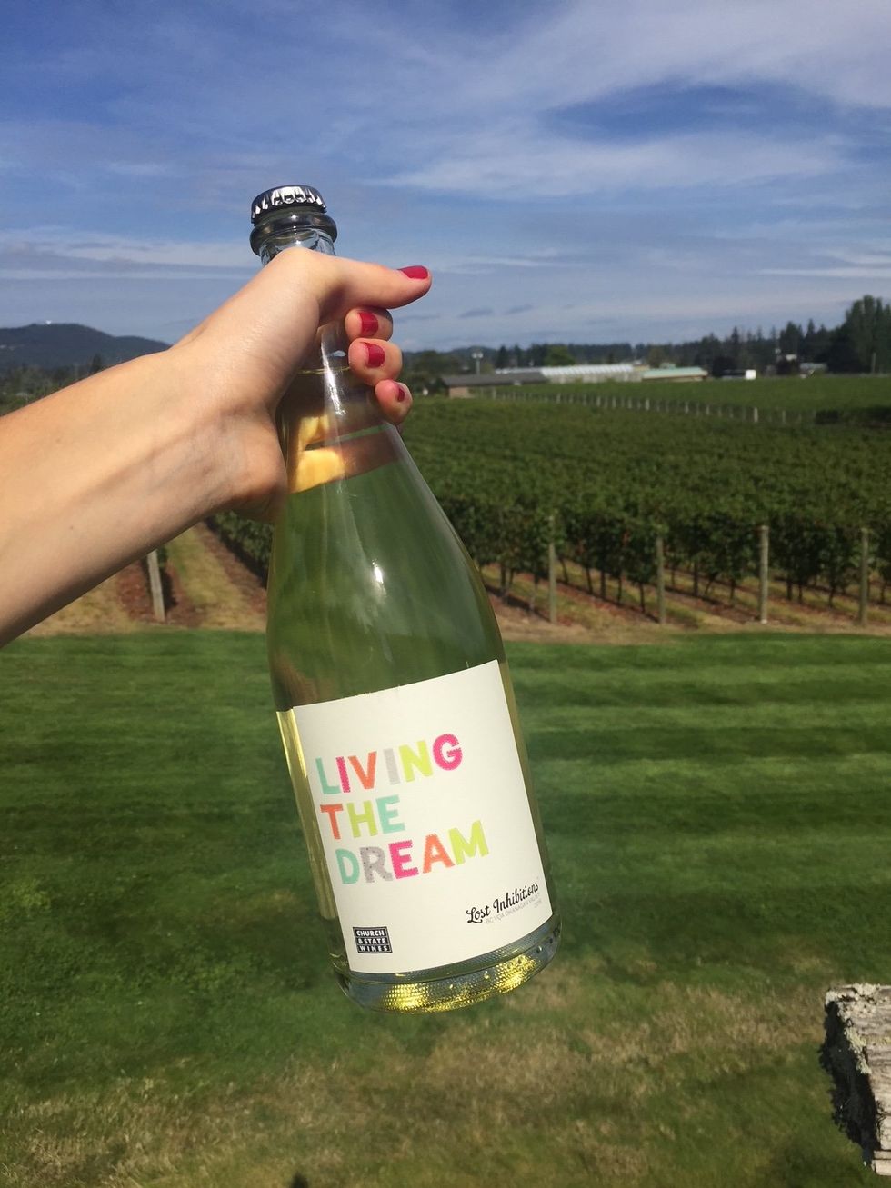 A hand holding a wine with a label that says "living the dream."