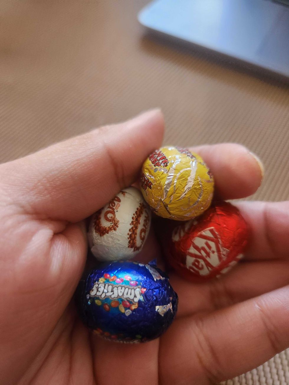 A hand holding Nestle Assorted Hide Me Eggs.