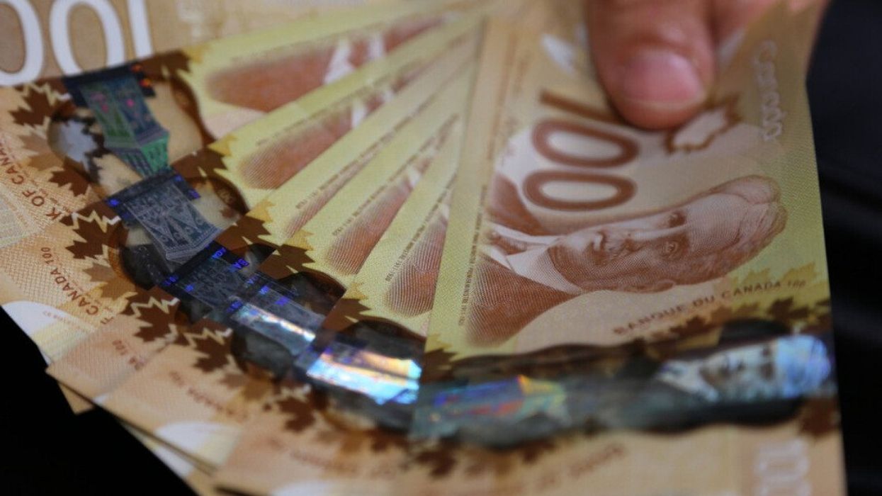 A hand holding several Canadian bills.
