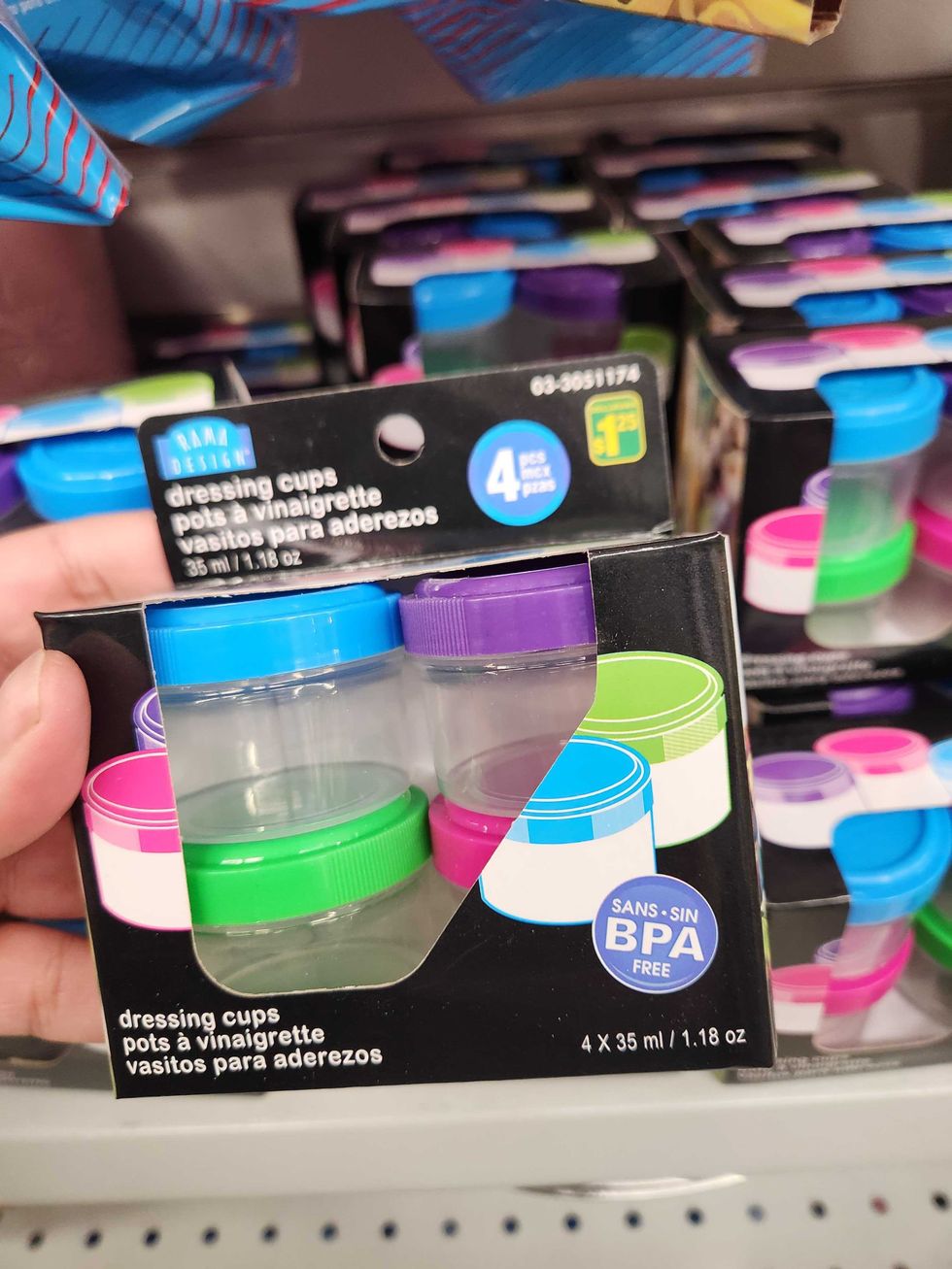 A hand holding tiny dressing cups.