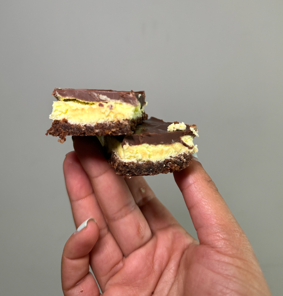 A hand holding two Nanaimo bars