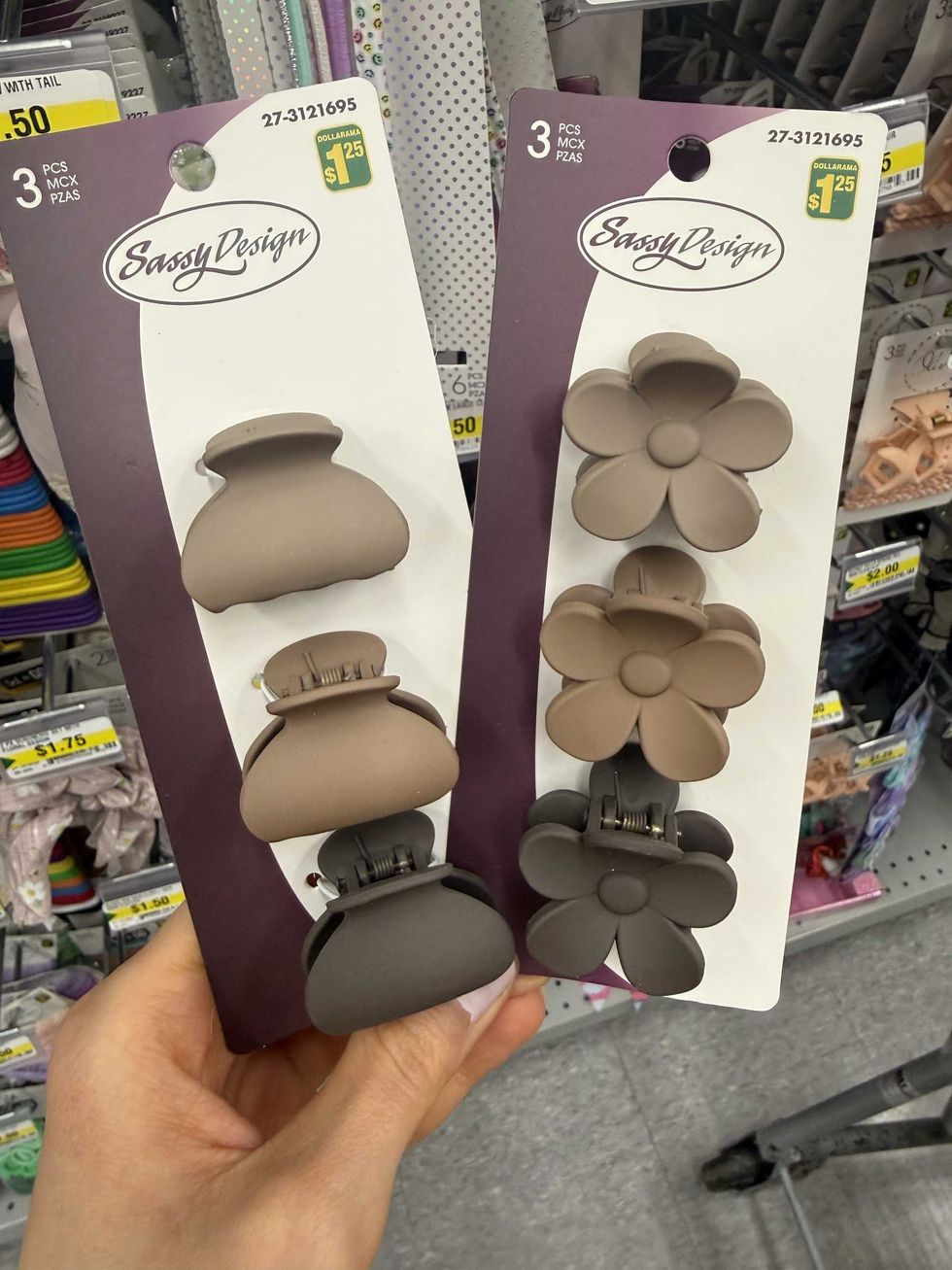 A hand holding various hair clips in different colours and shapes.